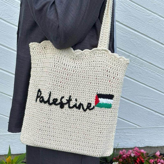 Cream handmade crochet tote bag with Palestine text and flag design, long shoulder straps.