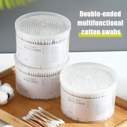 Three transparent plastic containers filled with white double-ended cotton swabs on a wooden surface.