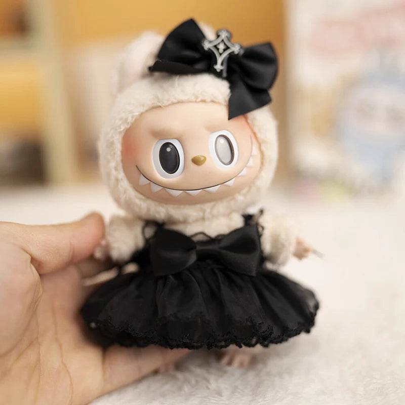 17cm doll wearing a fluffy cream hood with a black bow and a black devil-themed dress with a tulle skirt.