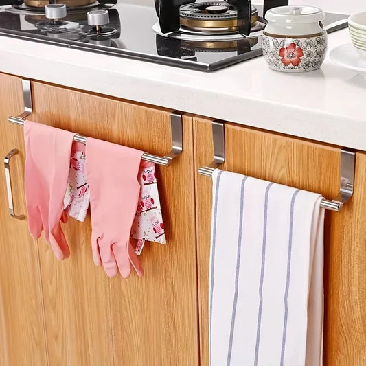 Kitchen cabinet with hanging gloves and towels, stove in the background
