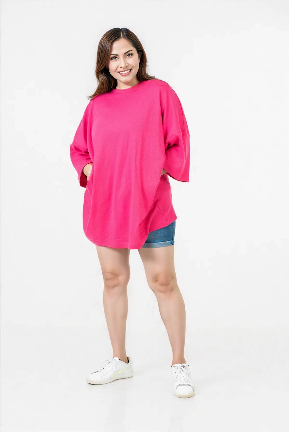 Bright pink relaxed fit t-shirt with dropped shoulders and short sleeves, paired with denim shorts and white sneakers.
