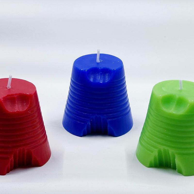 Set of three Huckabuck candles in red, blue, and green with ridged texture and wick on top.