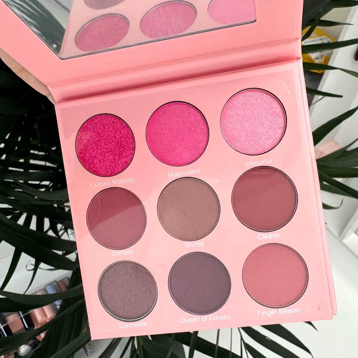 Pink eyeshadow palette with nine matte and shimmer shades ranging from bright pink to mauve and brown tones.