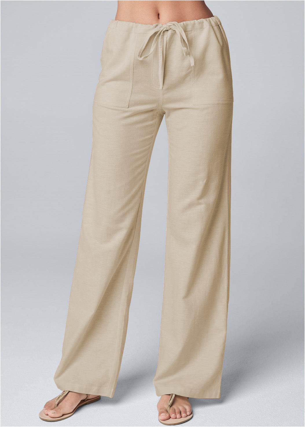 Beige loose cotton-linen pants with lace-up waist and straight wide legs.