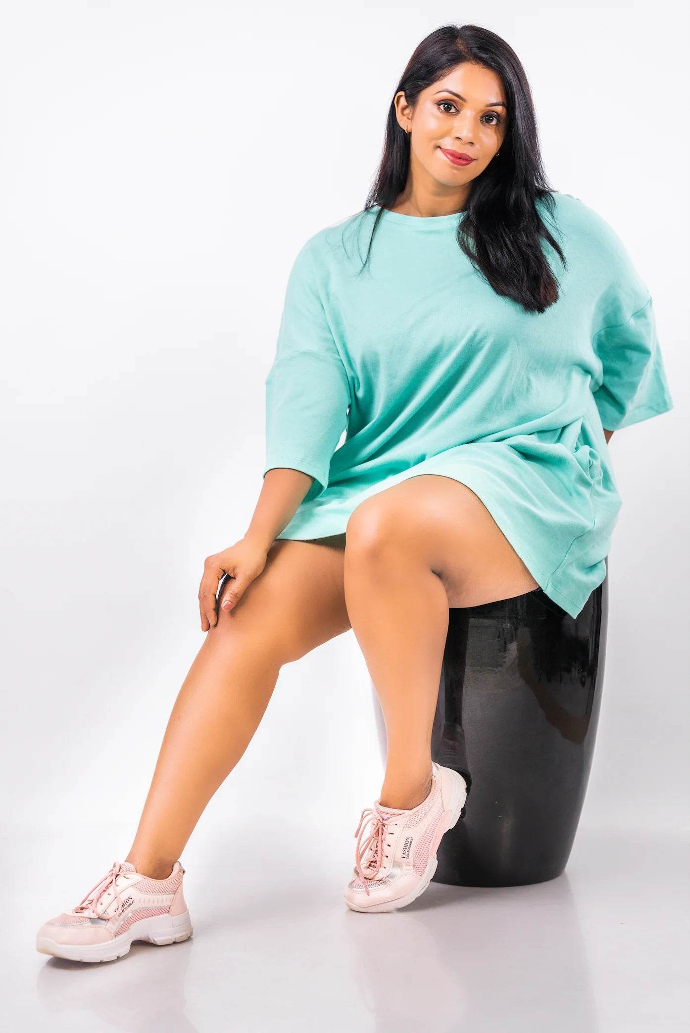 Relaxed fit light teal oversized t-shirt worn as a dress with white sneakers.