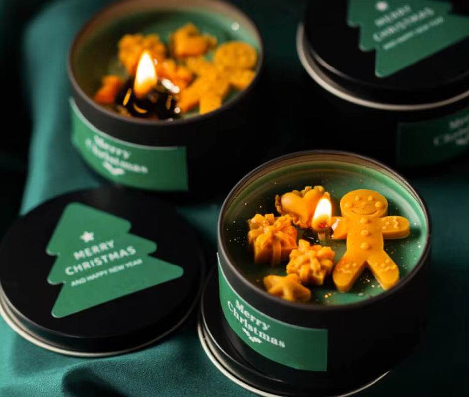 Green soy wax candle in black tin with vanilla scent, topped with festive gingerbread-shaped decorations and green Christmas .