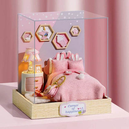 Miniature pink-themed dollhouse bedroom with a cozy bed, stuffed bunny, wooden bedside table, lamp, and hexagonal wall.
