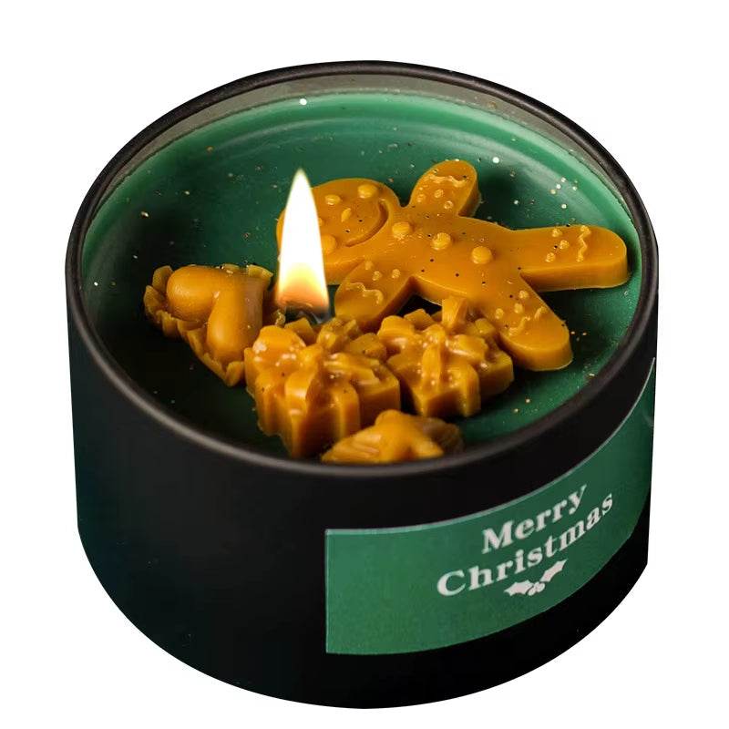 Black tin candle with lit wick, green label reading "Merry Christmas," and melted gingerbread man and snowflake-shaped soy.
