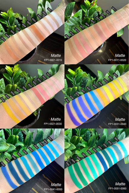 Swatches of six matte eyeshadow palettes with warm neutrals, pinks, yellows, blues, and greens on skin with greenery.
