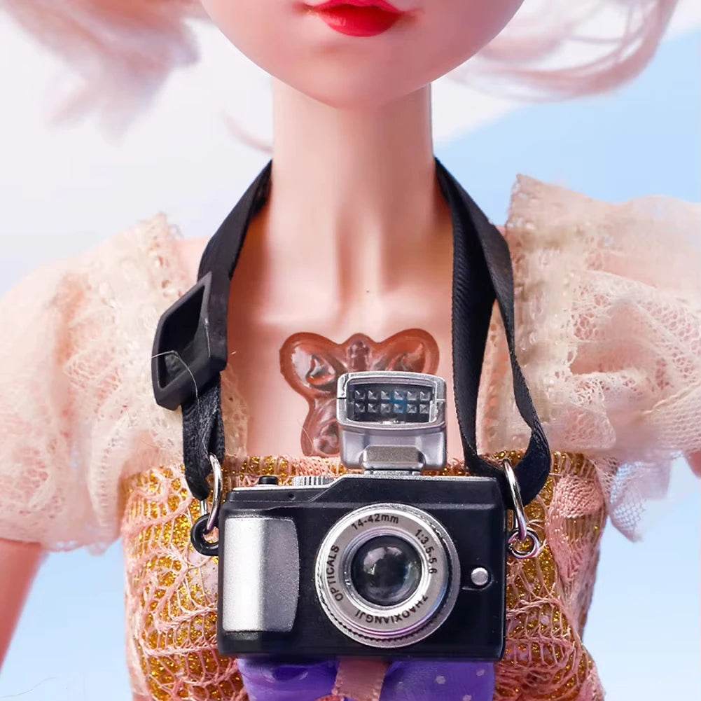 Black vintage-style camera with silver lens and flash hanging on doll wearing pink lace dress.