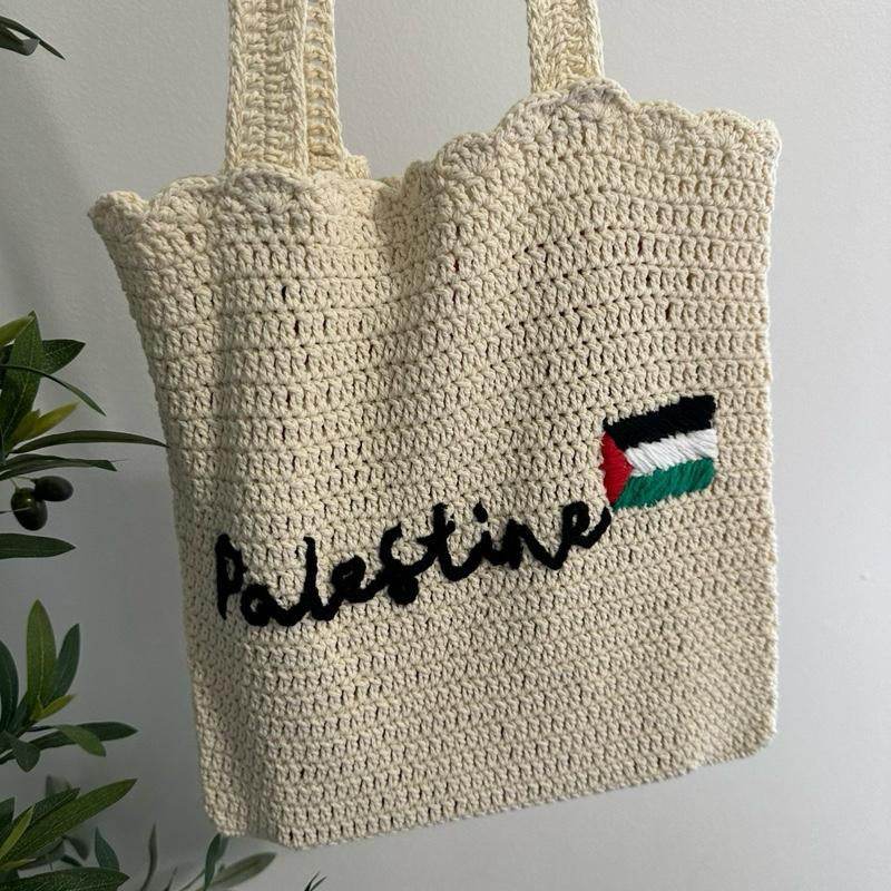 Cream-colored handmade crochet tote bag with "Palestine" text and Palestinian flag embroidery.