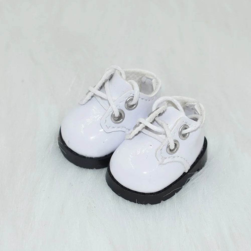 White lace-up doll shoes with black soles on a light background.