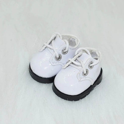 White lace-up doll shoes with black soles on a light background.