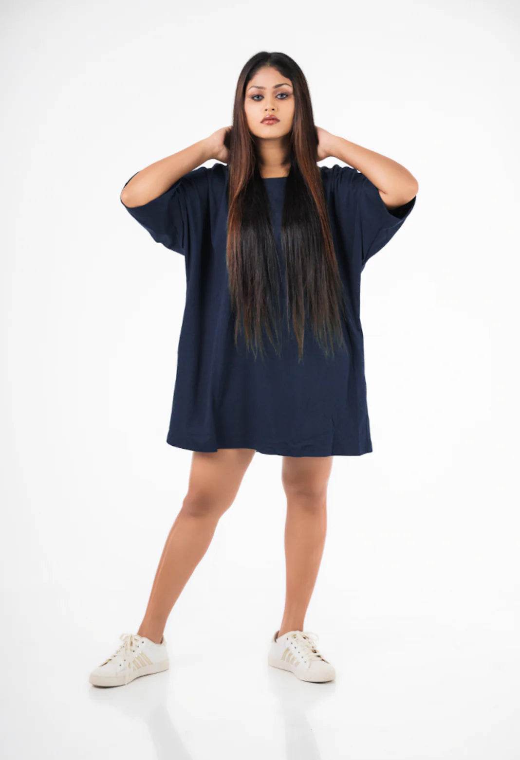 Navy blue relaxed fit oversized t-shirt worn as a dress paired with white sneakers.