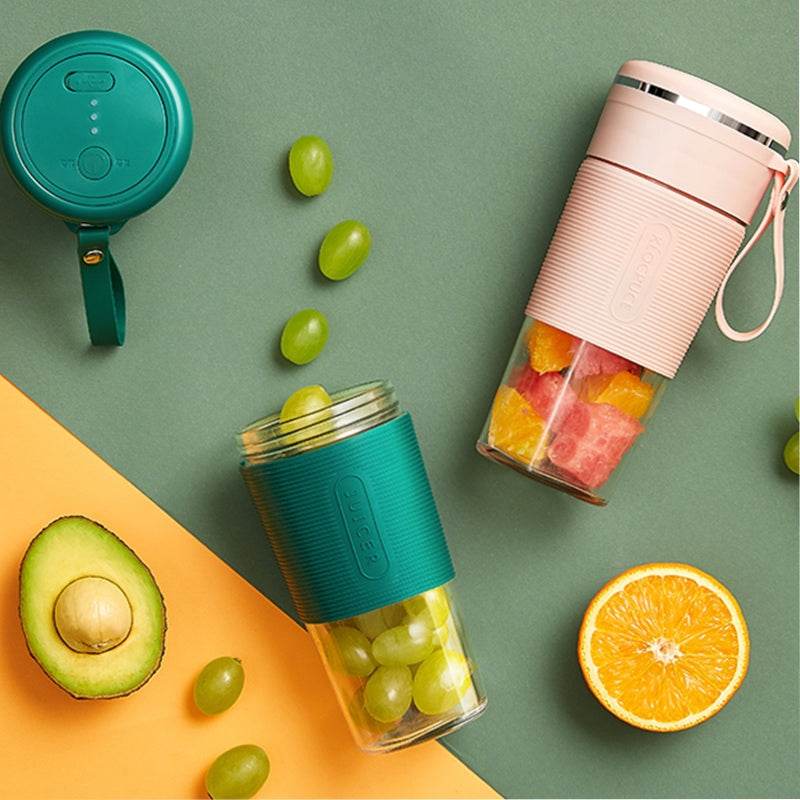 Green and pink portable blenders filled with grapes and fruit chunks on colorful background.