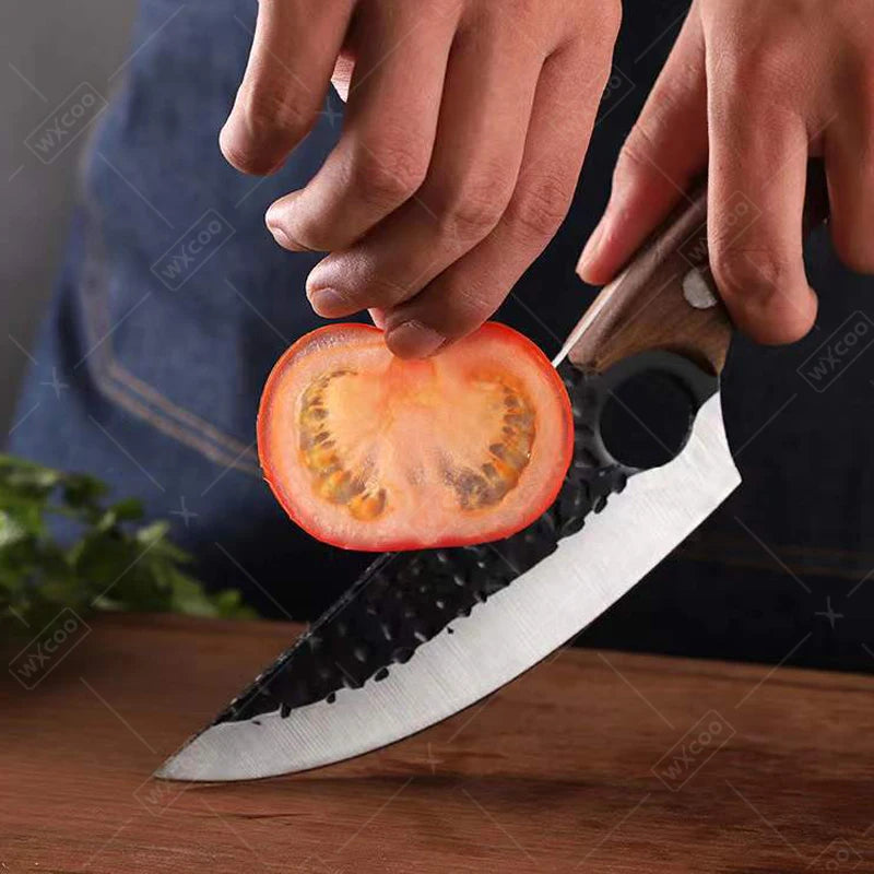Person holding a sliced tomato next to a knife on a wooden surface