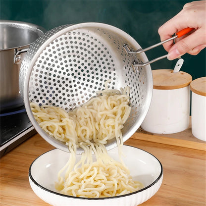 Person transferring cooked noodles from a perforated metal strainer into a bowl on a kitchen counter.