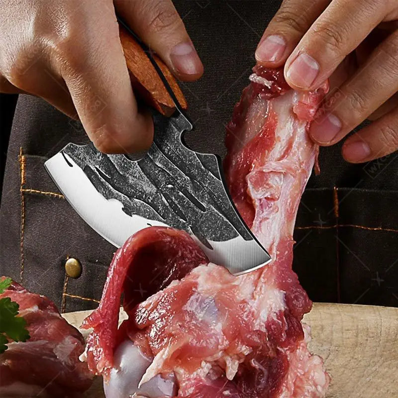 Person cutting raw meat with a cleaver on a wooden surface