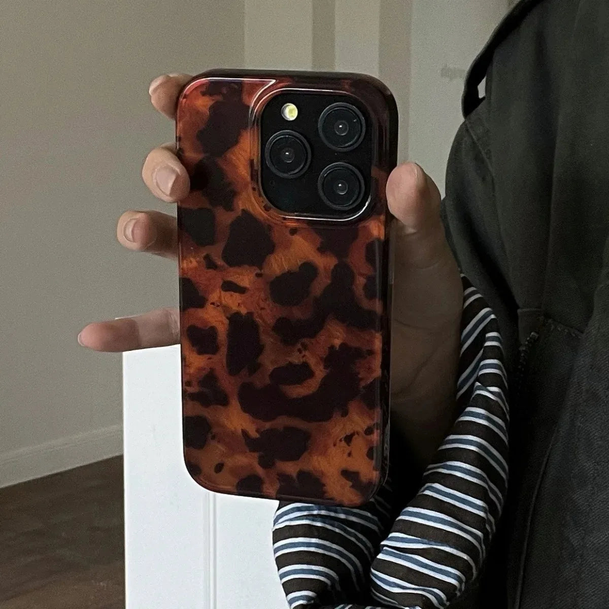 Person holding a phone with a leopard print case indoors