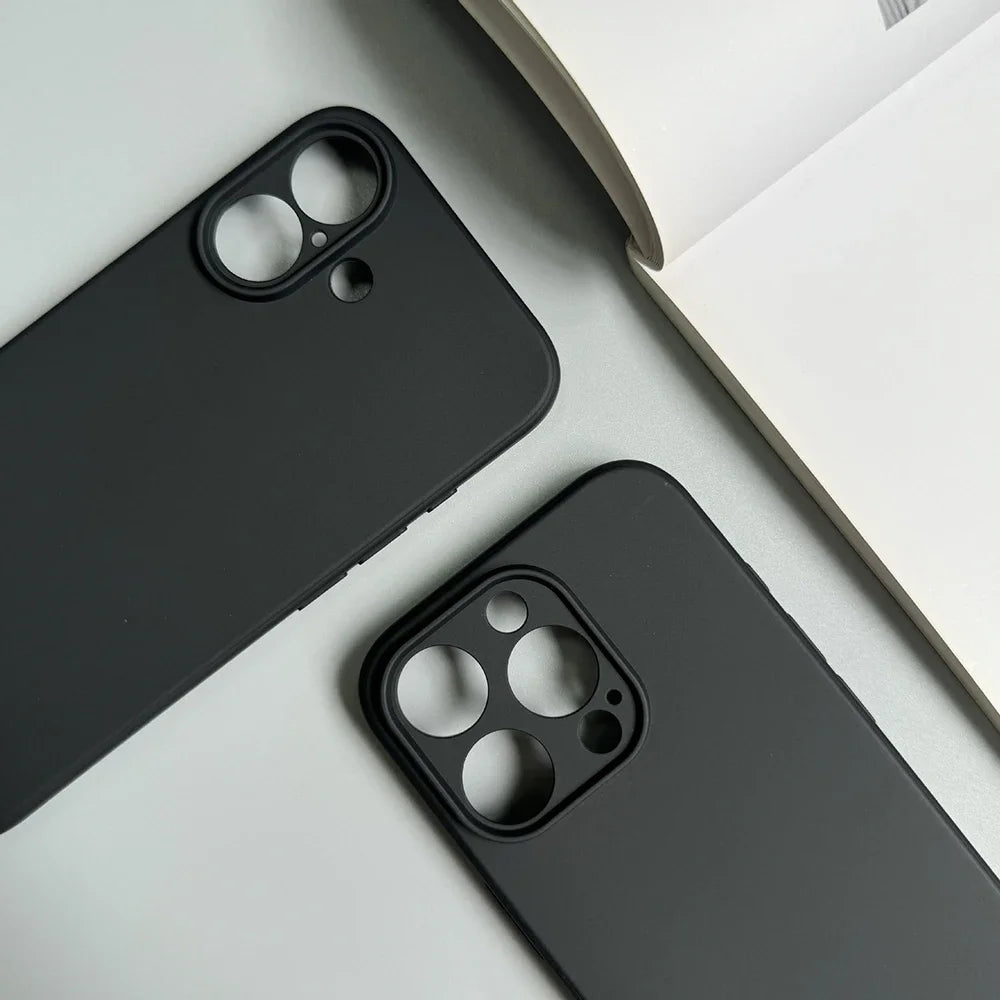 Two black phone cases on a light gray surface with a white book.
