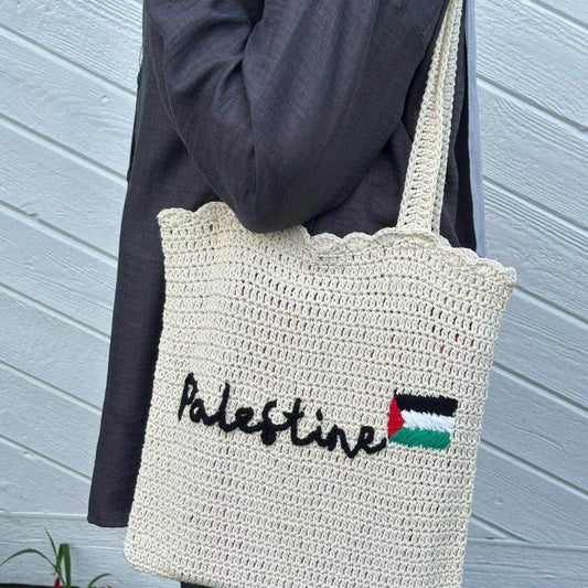 Cream crochet tote bag with scalloped edges, black "Palestine" text, and Palestinian flag embroidery.