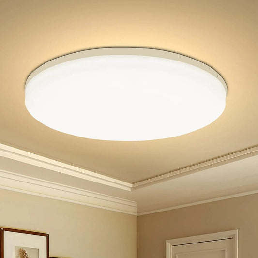 Round flush-mount LED ceiling light with white diffuser emitting warm white glow in beige room.