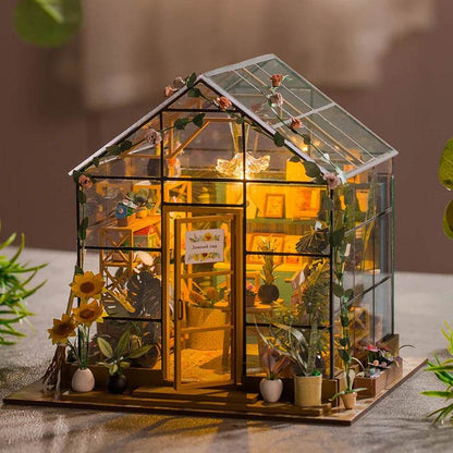 Miniature DIY flower house dollhouse with glass walls, roof, warm interior lighting, and detailed furniture.