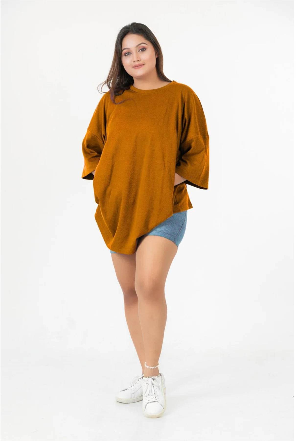 Rust-colored relaxed fit t-shirt with three-quarter sleeves paired with denim shorts and white sneakers.