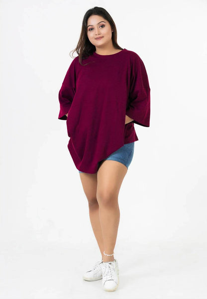 Maroon relaxed fit t-shirt with dropped shoulders and three-quarter sleeves worn with denim shorts and white sneakers.