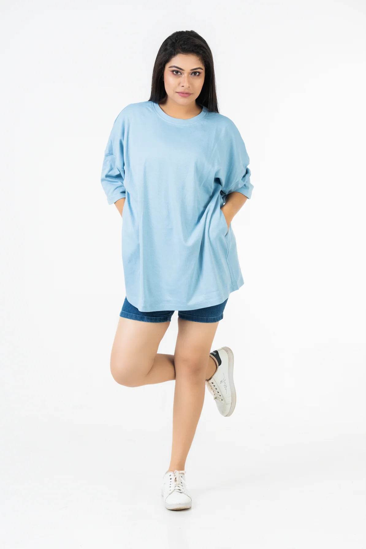 Light blue relaxed fit t-shirt with dropped shoulders paired with navy shorts and white sneakers.