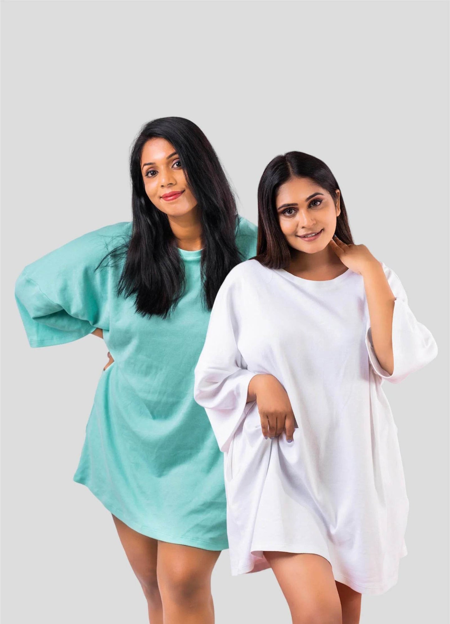 Two women wearing oversized relaxed fit t-shirts, one in light teal and the other in white, both with long sleeves and.