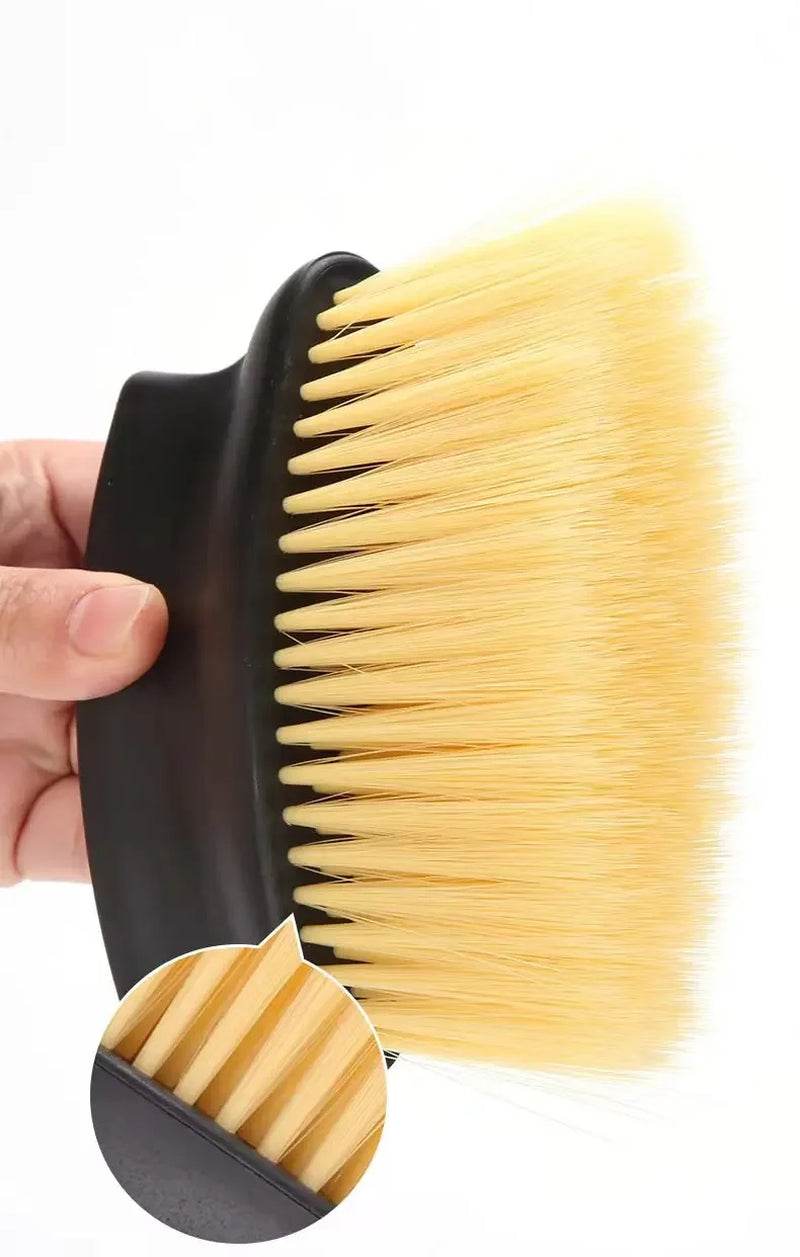 Soft yellow bristle car interior dust brush with black ergonomic handle held in hand.
