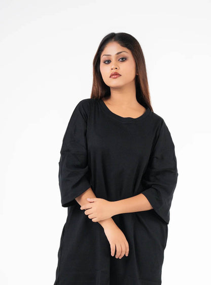 Relaxed fit black t-shirt with dropped shoulders and three-quarter sleeves on model.