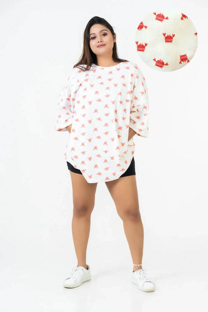 White relaxed fit t-shirt with all-over red crab print, worn with black shorts and white sneakers.