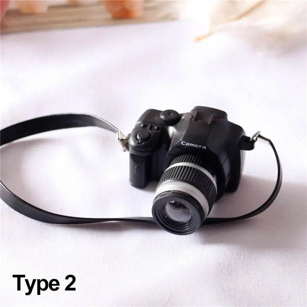 Black miniature DSLR camera toy with detailed lens and attached strap on white background.