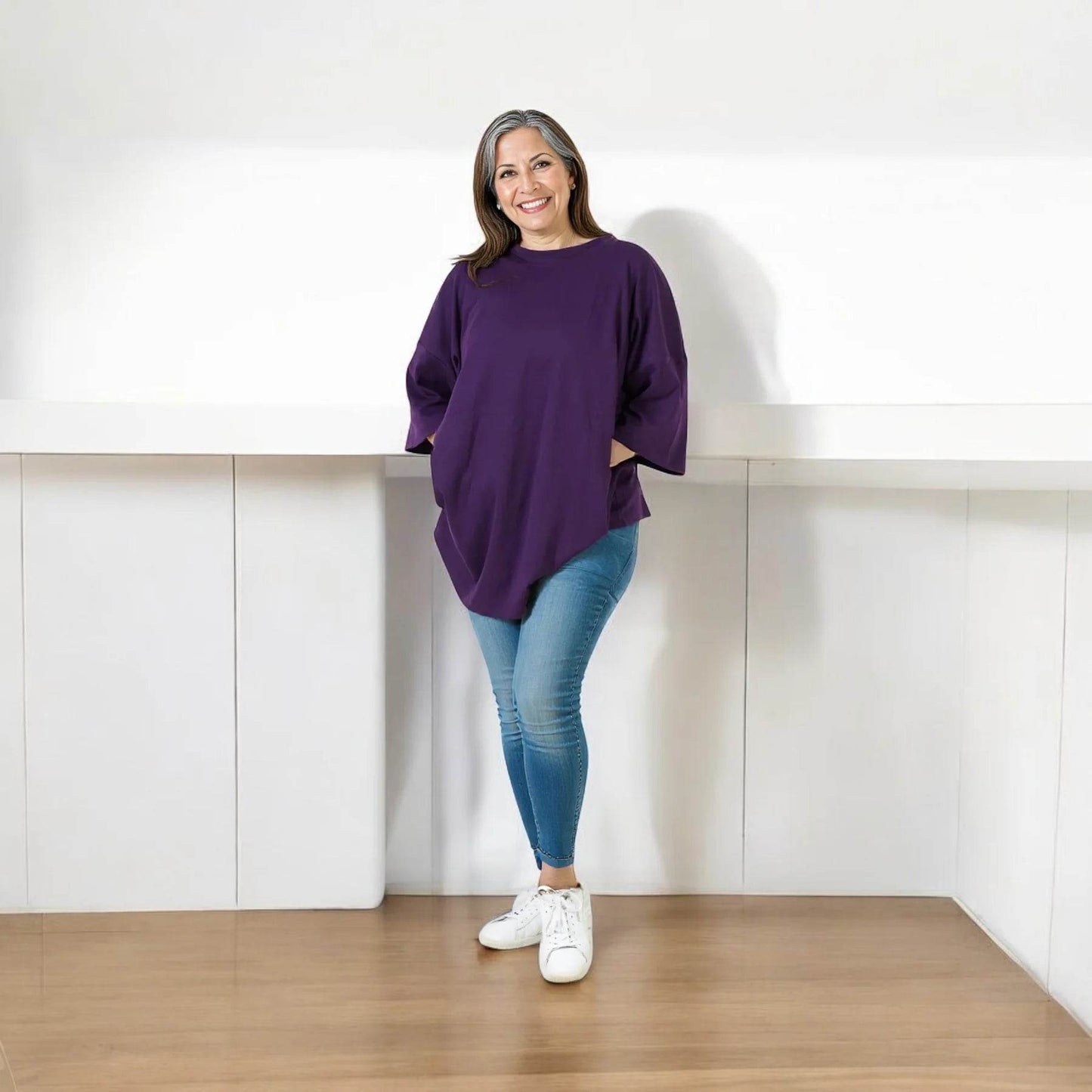Purple relaxed fit t-shirt with elbow-length sleeves worn with light blue jeans and white sneakers.