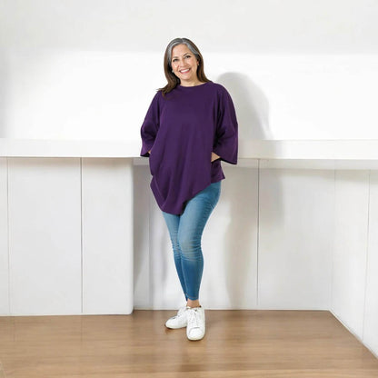 Purple relaxed fit t-shirt with elbow-length sleeves worn with light blue jeans and white sneakers.