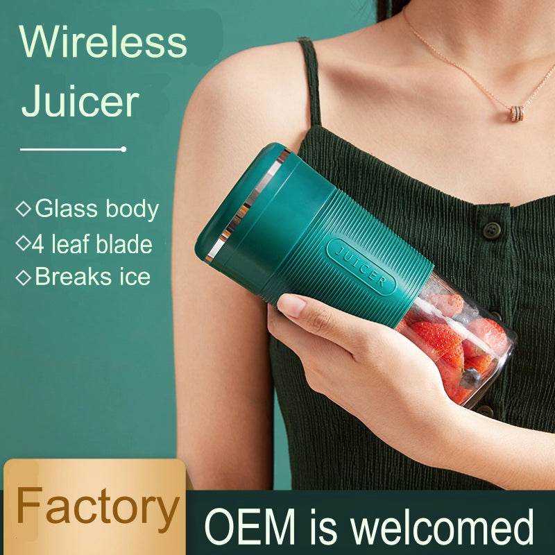 Green portable blender with glass body and metallic accents, held in hand with red and white fruit inside.
