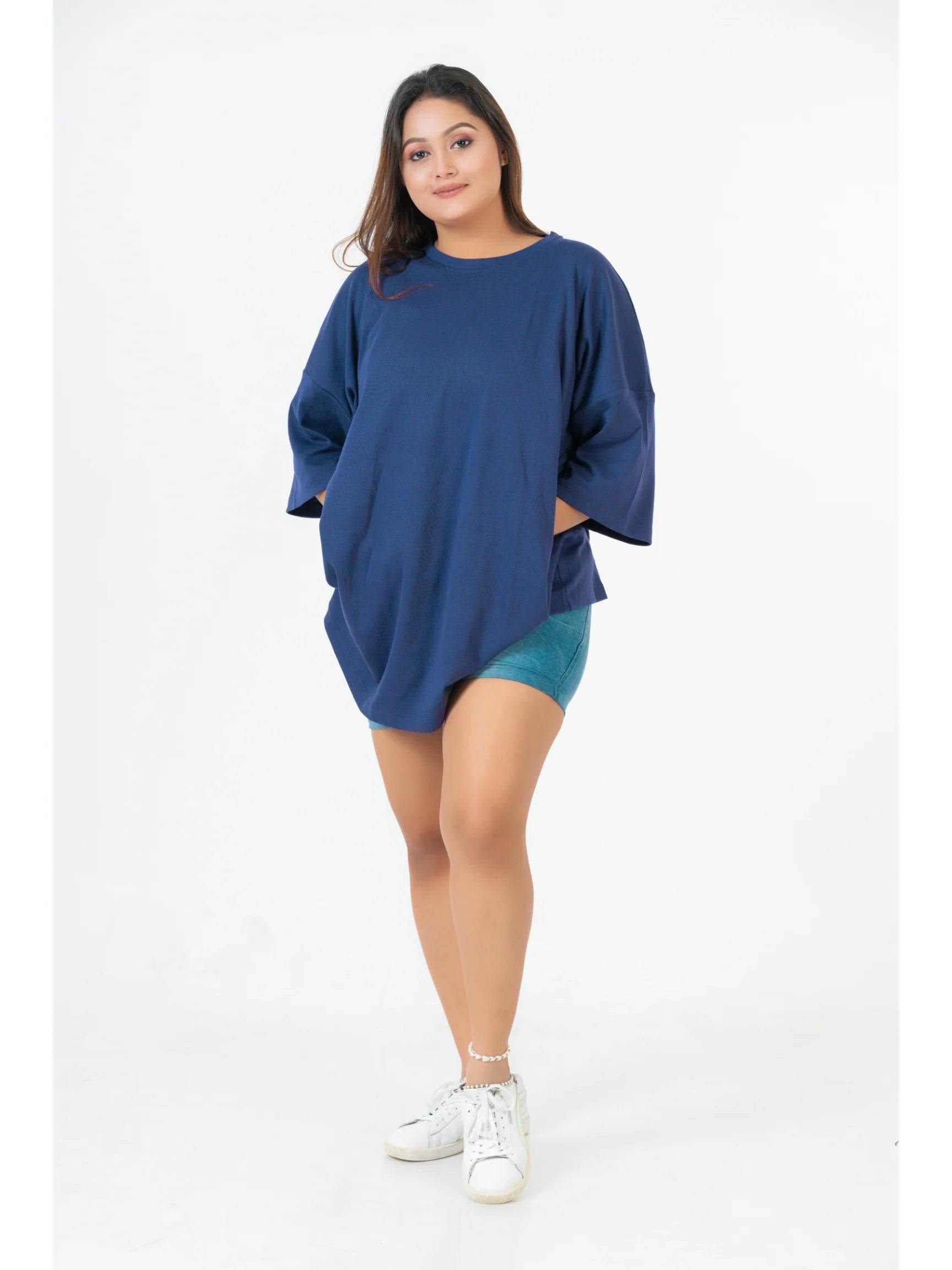 Navy blue relaxed fit t-shirt with wide sleeves worn with teal shorts and white sneakers.